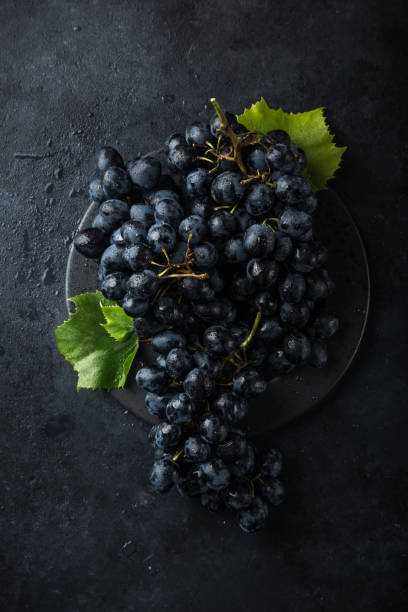 istock fresh ripe black grapes on dark concrete background 894372378
