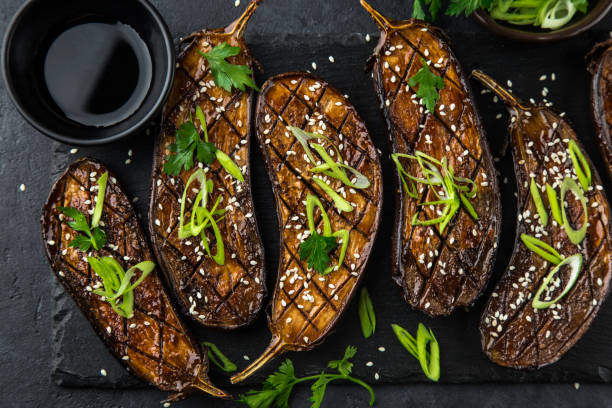 glazed grilled eggplants served with sesame seeds and green onion grilled glazed eggplants on black background, top view miso sauce stock pictures, royalty-free photos & images