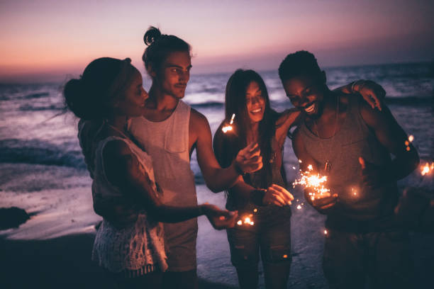 istock Young multi-ethnic couples celebrating with sparklers at beach after sunset 894372868