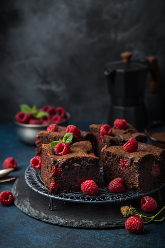 raspberry brownies served  with fresh berries, dark background, selective focus