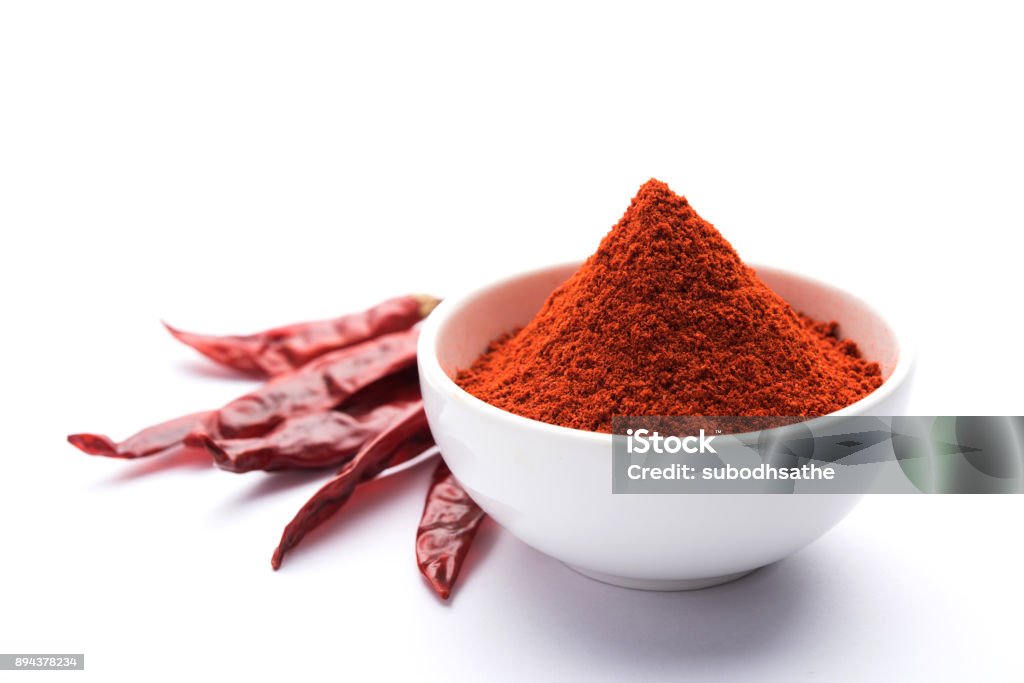 Red Chilli Powder in a bowl with dried red chillies over colourful background or pile of red chilli powder over plain background Paprika Stock Photo