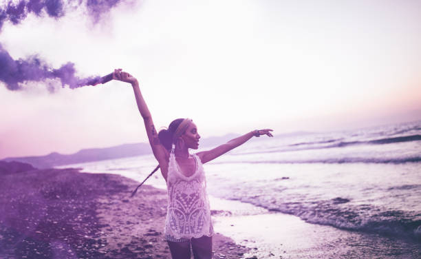 mulher jovem hippie comemorando com bomba de fumaça na praia - 3141 - fotografias e filmes do acervo