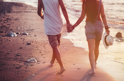 Close-up of romantic hipster couple on island summer holidays walking on beach and holding hands