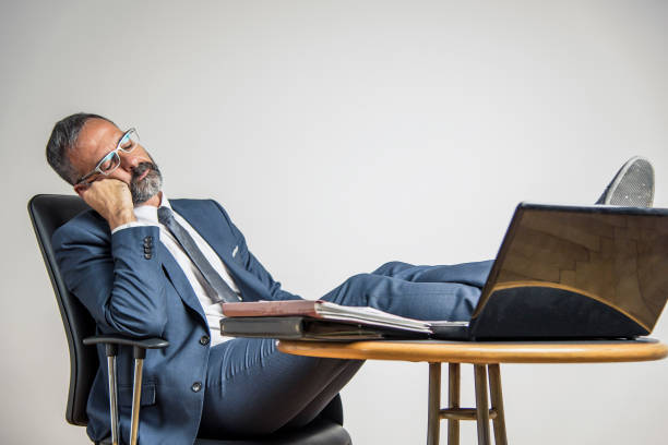Boring job being a boss Bored business man is sleeping in his office, lying in his chair with his legs on his office desk sleeping grandpa stock pictures, royalty-free photos & images