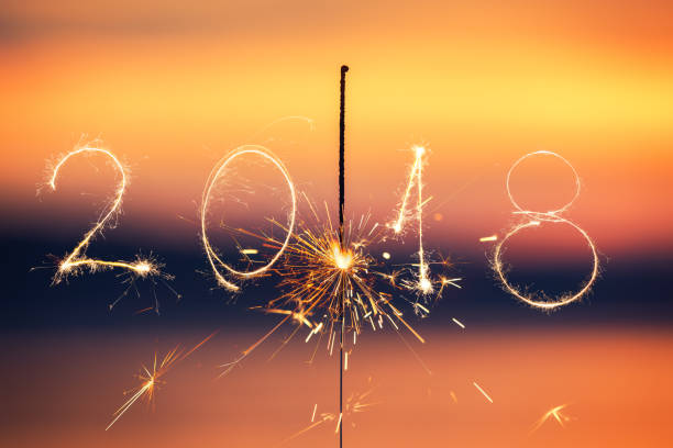 istock 2018 written with Sparkle firework on sunset background, happy new year 2018 concept 894409706
