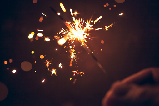 Person celebrating at night by holding sparkler.