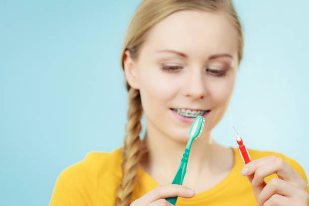 istock Girl with teeth braces using interdental and traditional brush 894420746