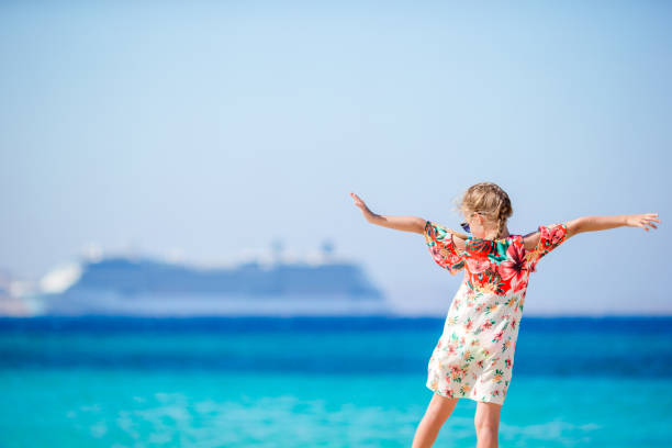Adorable little girl at beach background big cruise lainer in Greece Adorable little girl at tropical beach on vacation cruise vacation stock pictures, royalty-free photos & images
