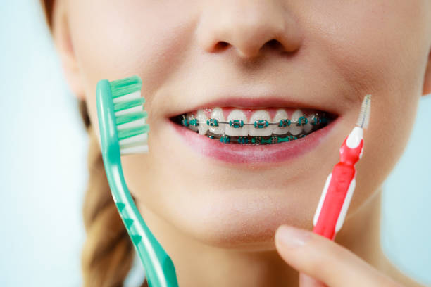 istock Girl with teeth braces using interdental and traditional brush 894435894