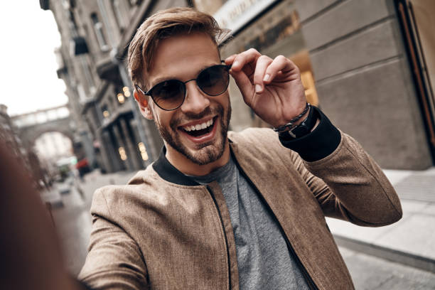Going crazy. Self portrait of handsome young man in casual wear smiling and adjusting his eyewear while standing outdoors stylish selfie stock pictures, royalty-free photos & images
