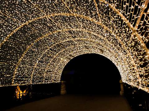 Wide angle color image depicting the Liar's Bridge illuminated at night in Sibiu, a medieval city in the Transylvania region of Romania. The bridge is totally covered with golden colored Christmas lights, Room for copy space.