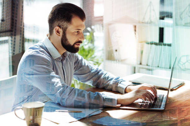 istock Young concentrated man sitting and working with laptop 894440404