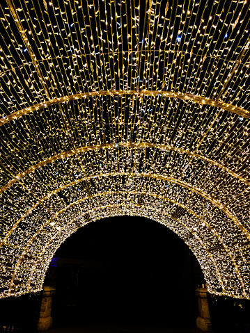 Wide angle color image depicting the Liar's Bridge illuminated at night in Sibiu, a medieval city in the Transylvania region of Romania. The bridge is totally covered with golden colored Christmas lights, Room for copy space.
