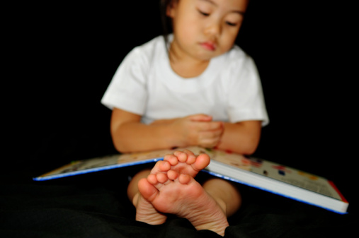 little girl reading a book with close up feets