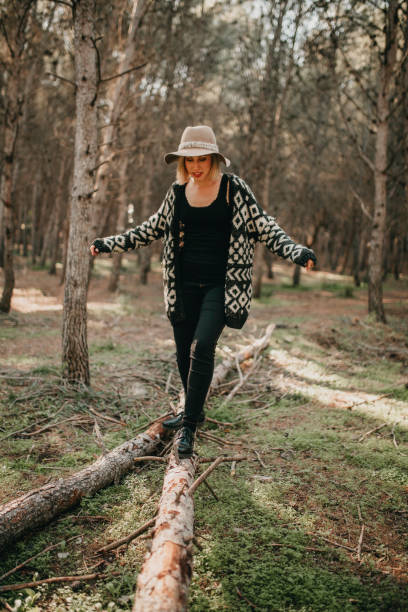 istock Woman in casual clothes walking on a fallen tree trunk in the forest. 894447498