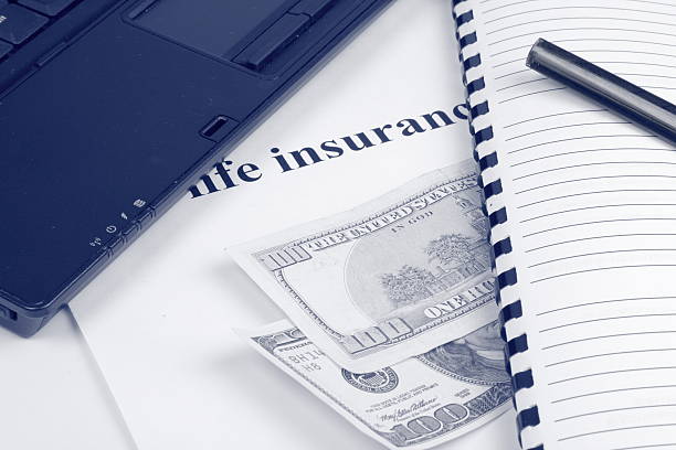 Blue toned notebook, pen, dollars, with "life insurance" words. stock photo