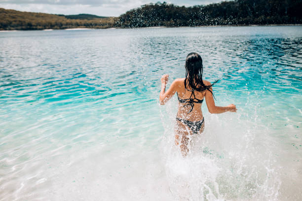 Running into Lake McKenzie Rear view of a young woman running into Lake McKenzie on Fraser Island in Queensland, Australia. fraser island stock pictures, royalty-free photos & images