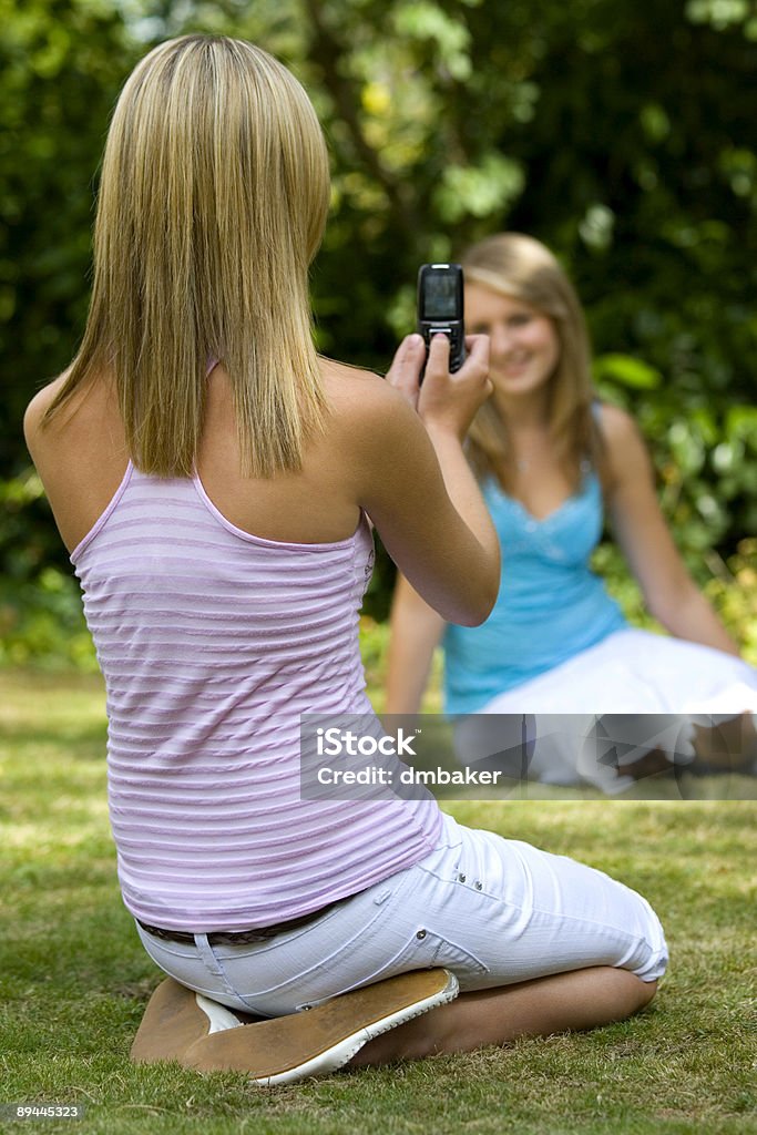 Deux filles en dehors à prendre des photos à l'aide d'un appareil photo de téléphone - Photo de Adolescent libre de droits