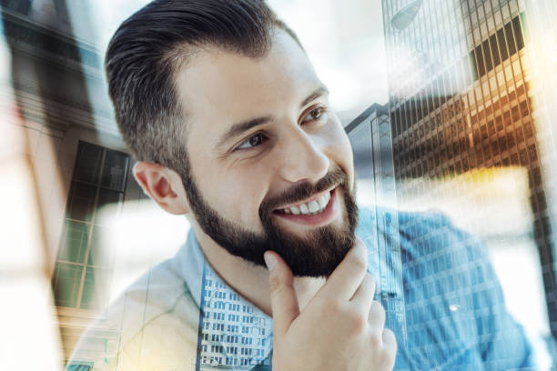 istock Young perspective man holding hand near beard and smiling 894457850