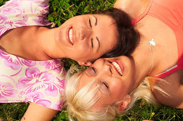 A closeup of two young girl lying on grass and having fun outdoor
