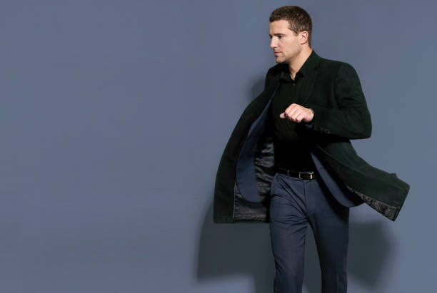 istock man in a black coat on a gray background studio 894461704