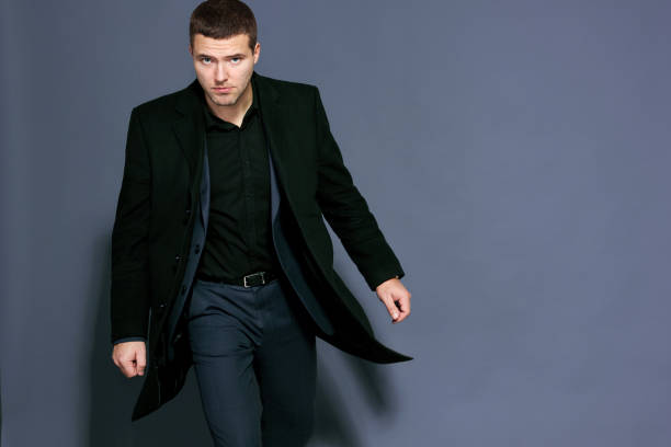 istock man in a black coat on a gray background studio 894461708