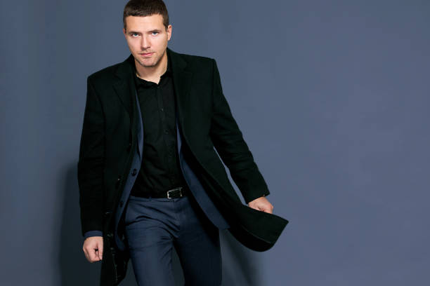 istock man in a black coat on a gray background studio 894463876