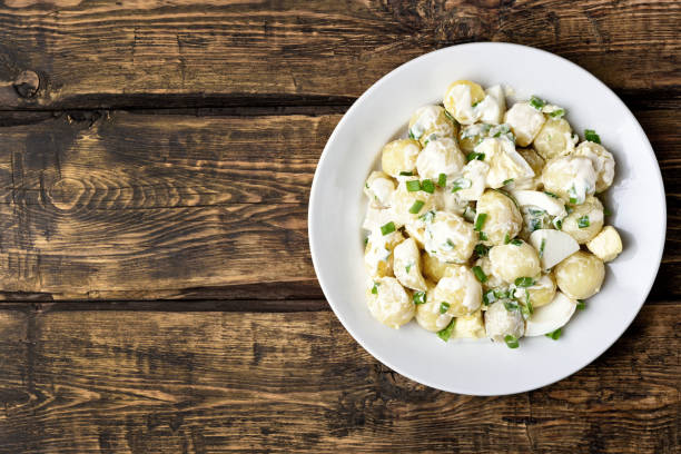 Potato salad with eggs and green onion Potato salad with eggs and green onion on white plate over wooden background with copy space. Top view, flat lay food chive photos stock pictures, royalty-free photos & images
