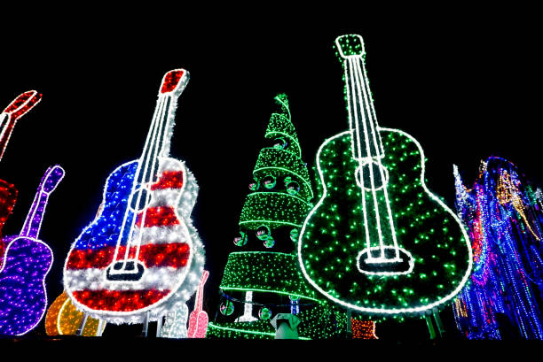AUSTIN, TEXAS USA- DECEMBER 11, 2017: Bright Red, White and Blue USA Flag Guitar and Purple and Green Guitars lit up with lights.  In the background there is a Holiday Tree with Ornaments lit up with green lights and colorful holiday lights at Mozart's Coffee Roasters Holiday Light Show on Lake Austin