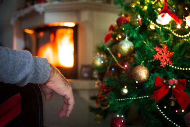 main de l’homme solitaire en face de la cheminée avec arbre de noël. - senior adult photograph photography family tree photos et images de collection