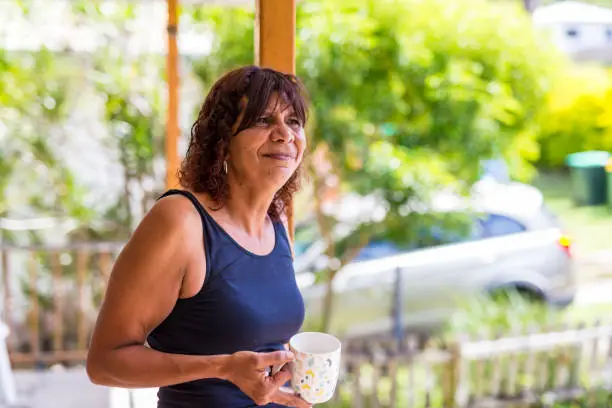 Australian Aboriginal mother outside on her balcony enjoying drinking a cup of coffee at home