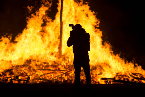 istock Photographer silhouette standing in front of a large bonfire 894471414