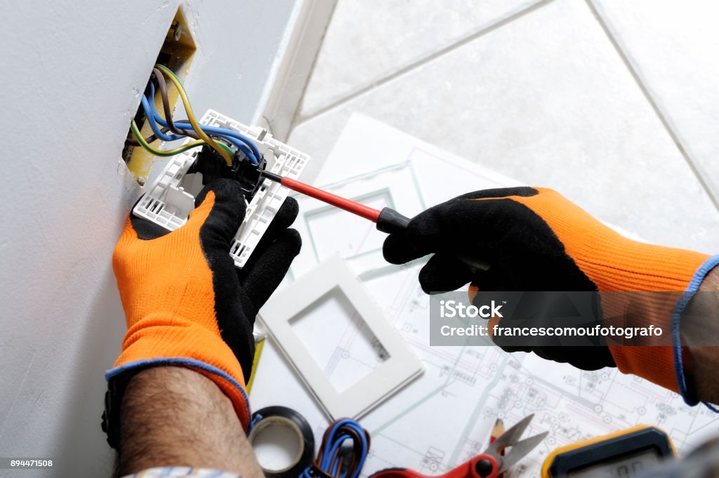 Electrician working in a residential electrical system Electrician working safely on switches and sockets of a residential electrical system Electrician Stock Photo