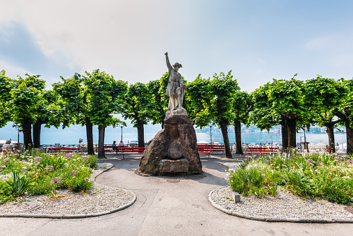 Lugano, Switzerland - May 28, 2016: Sculpture of William Tell at the promenade of the luxurious resort in Lugano on Lake Lugano and Alps mountains in Ticino canton of Switzerland.
