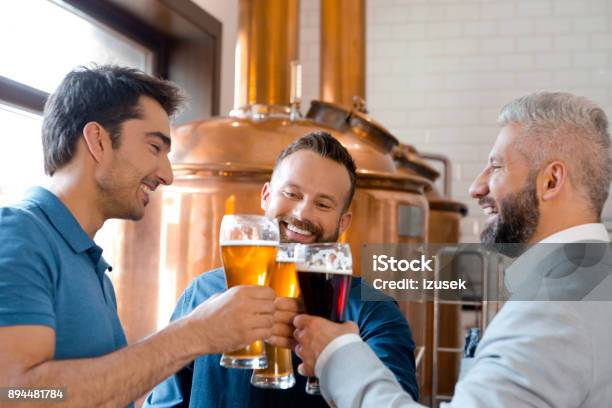 Three Men Toasting Beers After Work At Micro Brewery Stock Photo - Download Image Now