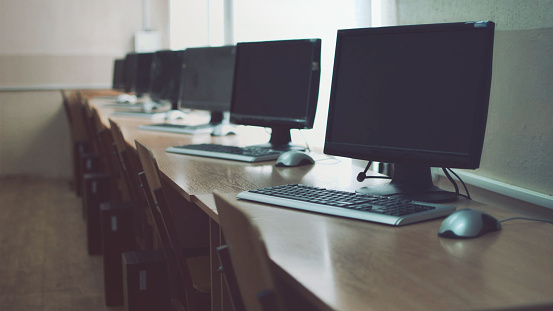 Computer monitors, education room, mouses and keyboards on the tables