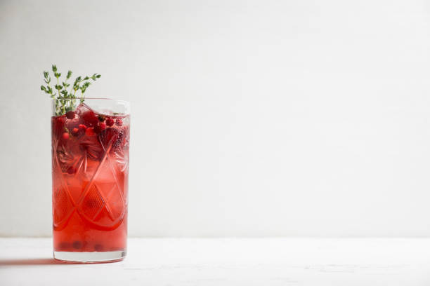 Christmas cocktail with berries and thyme on the rustic background Christmas cocktail with berries and thyme on the rustic background. Selective focus. cowberry stock pictures, royalty-free photos & images