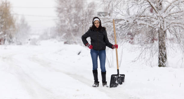 istock Girl with a shovel cleans the snow 894542484