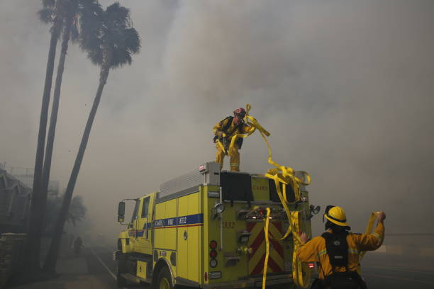 les pompiers en la faria, california déploient lances pour éteindre les flammes dans un palmier au-dessus d’une maison de plage que le thomas fire hurle à travers la région. - 2017 photos et images de collection