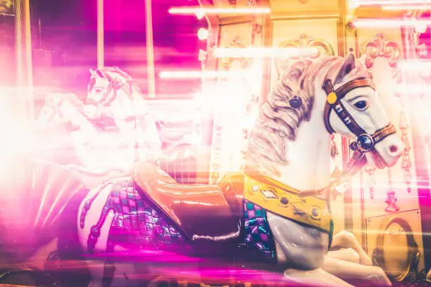Photo of Nostalgic Horse Detail of Carousel Spinning with Pink Light Blurs