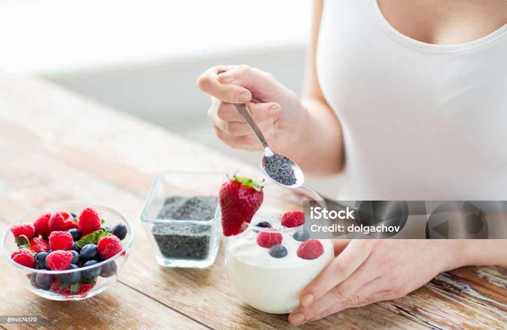 cerca de las manos de mujer con yogur y bayas - Foto de stock de Semilla de salvia hispánica libre de derechos