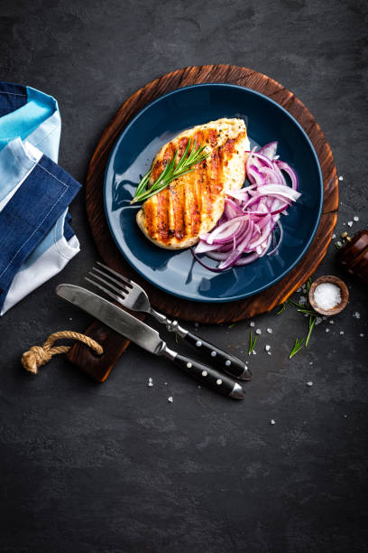 istock Juicy grilled chicken meat, fillet with fresh marinated onion on plate. Black background, top view 894593006