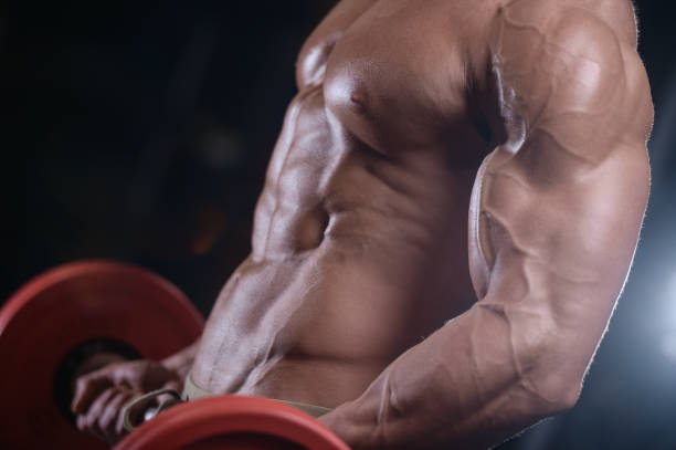 istock sexy strong bodybuilder athletic men pumping up muscles with dumbbells 894593676