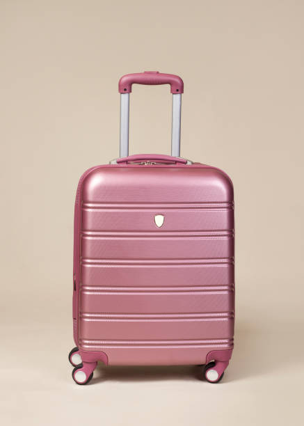 istock Pink trolley suitcase isolated on beige background 894600136