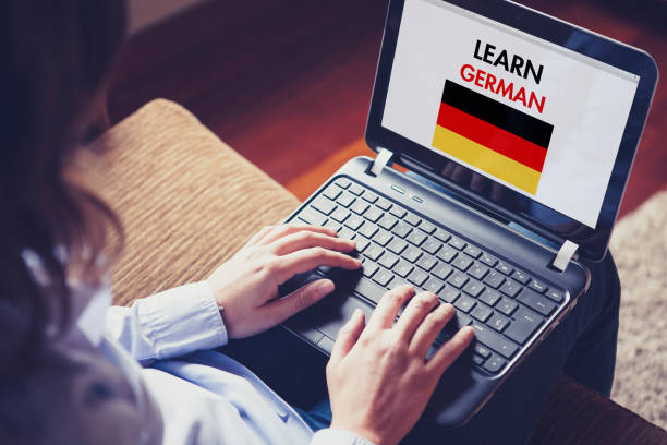 donna che impara il tedesco a casa con un laptop. - text talking translation learning foto e immagini stock