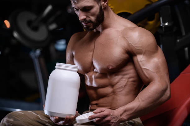 istock sexy strong bodybuilder athletic men pumping up muscles with dumbbells 894606608