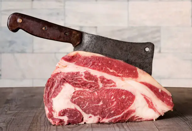 Raw prime rib beef with meat cleaver.