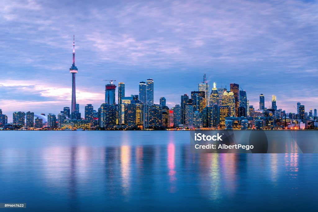 Toronto Skyline under Cloudy Sky at Dusk Spectacular View of Downtown Toronto under Cloudy Sky at Dusk with Lights Reflecting in Water. Ontario, Canada. Toronto Stock Photo