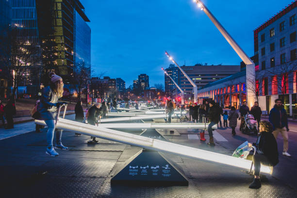Place Des Arts Square are Night with Kids and Parents having Fun on Seesaws that Change Light Intensity and also Makes Music. stock photo