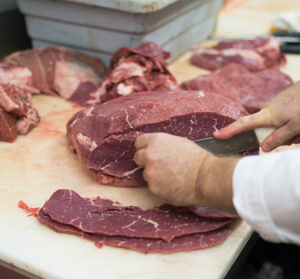 istock Butcher cutting top round steak 894662208
